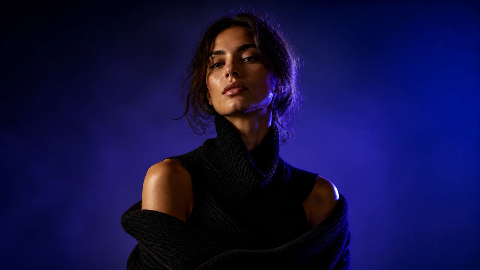 Fashion portrait in sculptural black knit against cobalt light